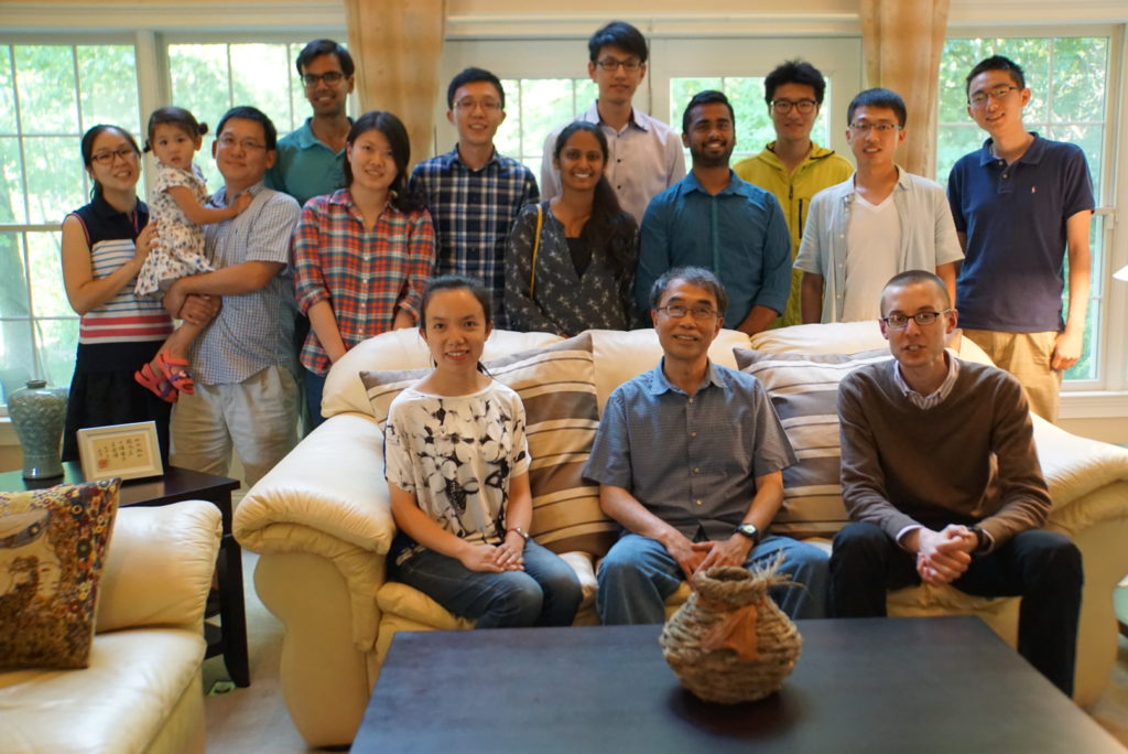 Group photo of people standing behind and sitting on a couch